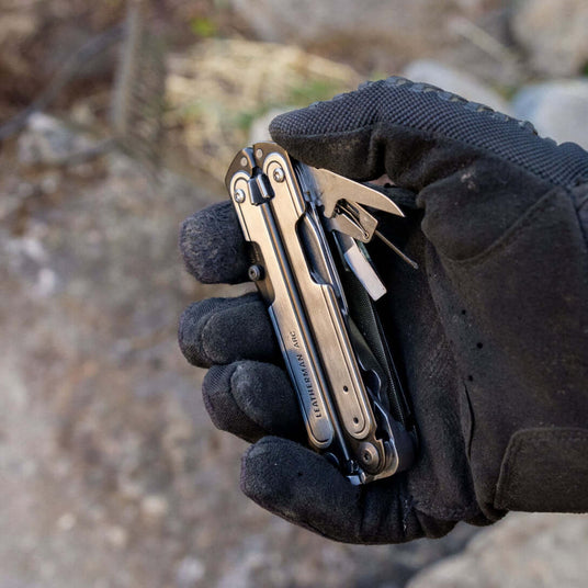 Black DLC & Stainless Steel Leatherman ARC® multi-tool in a gloved hand, ready for outdoor use.
