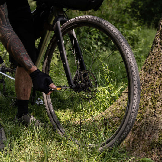 Translation missing: en.Person repairing a bicycle’s front wheel outdoors using Leatherman Signal