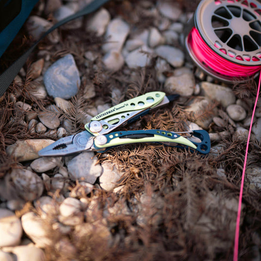 Verdant Skeletool® CX multi-tool on rocky surface with fishing line roll in background.