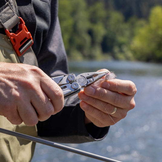 Person using a Stainless Steel Leatherman Wave® Plus multitool for fishing on the river.