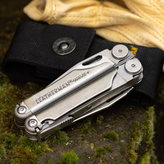 Leatherman Wave® Plus multi-tool with black nylon sheath on a mossy surface, showcasing its versatility and durability.
