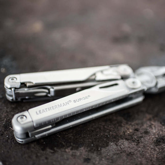 Close-up of a Stainless Steel Leatherman Surge® multitool on a dark surface, showcasing its sleek design.