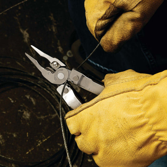 Hands in yellow gloves using a Stainless Steel Leatherman Rebar® multitool to cut wire.