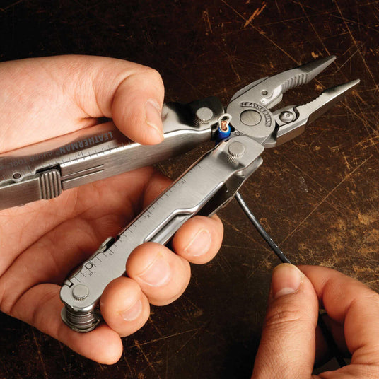 Person using a Stainless Steel Leatherman Super Tool® 300 multitool for electrical work.