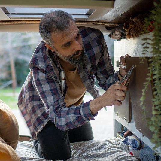 Man using a Mesa Verde Leatherman Signal® tool inside a van for home improvement and repairs.