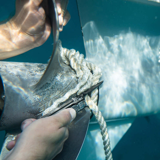User cutting rope underwater with a Black DLC & Stainless Steel Leatherman ARC® tool.