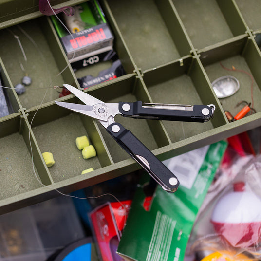 Translation missing: en.A fishing box supports a pair of Leatherman Micra indicating a workspace for cutting or organizing materials