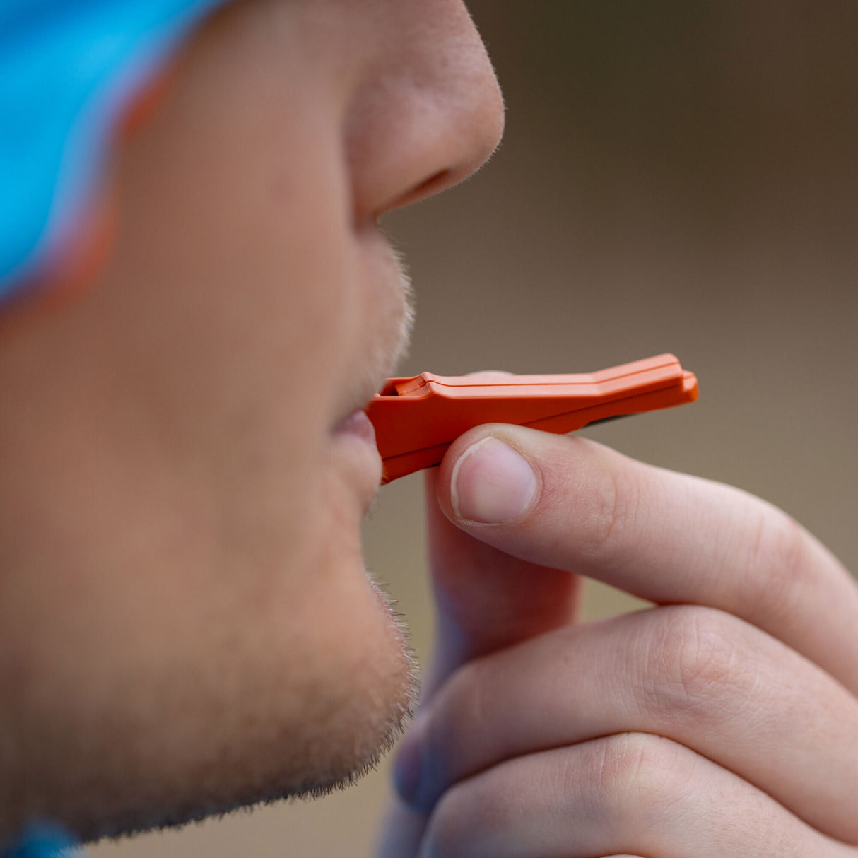 Translation missing: en.A man blowing Leatherman Signal whistle.