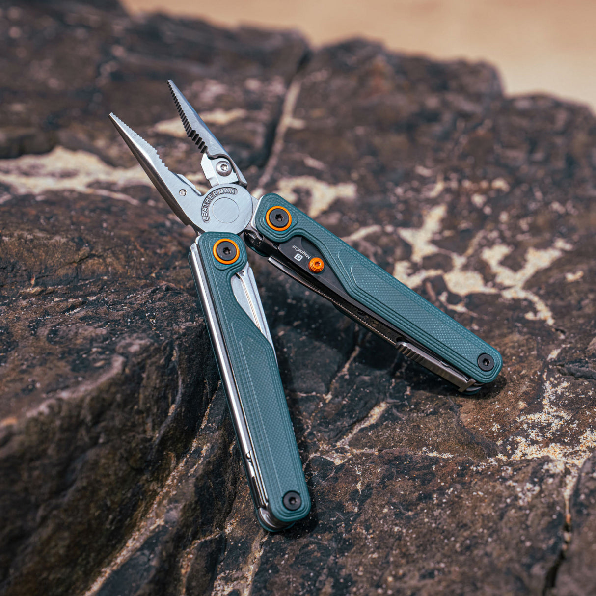 Translation missing: en.Leatherman Wave® Alpha Cascadia multi-tool with pliers extended, placed on a rock in an outdoor setting