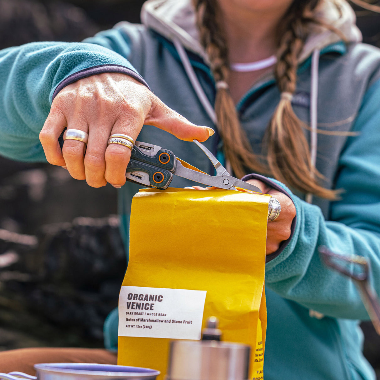 Translation missing: en.Person using the scissors on the Leatherman Wave® Alpha Cascadia multi-tool to open a bag of coffee beans outdoors