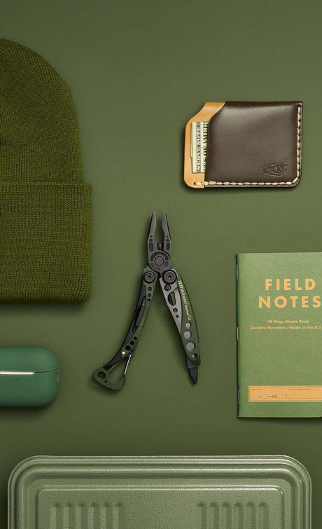 A green Skeletool CX open showing pliers laying on a green background surrounded by green objects.