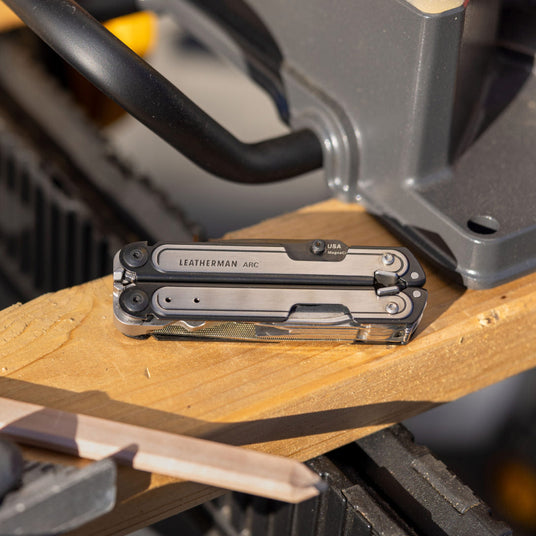 Black DLC & Stainless Steel Leatherman ARC® multitool resting on a wooden surface, ideal for DIY projects and outdoor adventures.