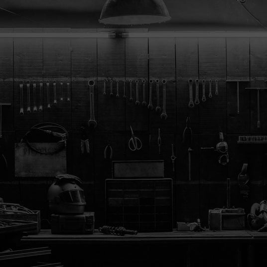 Translation missing: en.A dimly lit workshop with various tools hanging on the wall, a workbench, and storage drawers