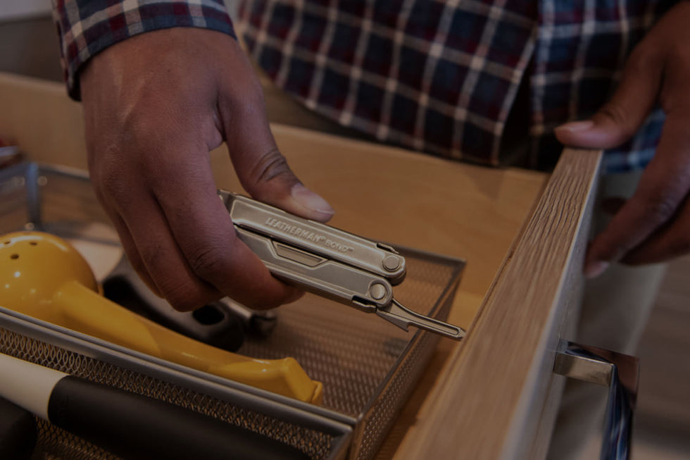 Translation missing: en.A person is seen holding a Leatherman Bond in a drawer, surrounded by assorted utensils
