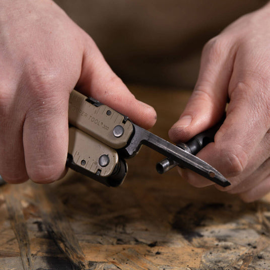 Translation missing: en.Someone using the carbon scraper on a coyote tan Leatherman Super Tool 300