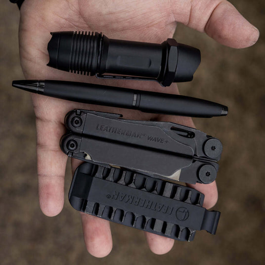 Translation missing: en.A black Leatherman Wave, Leatherman bit kit, pen and a flashlight in the palm of a hand