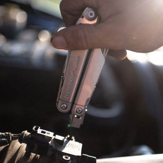 Stainless Steel Leatherman Surge® multitool in use on a vehicle engine, showcasing its versatility and functionality.