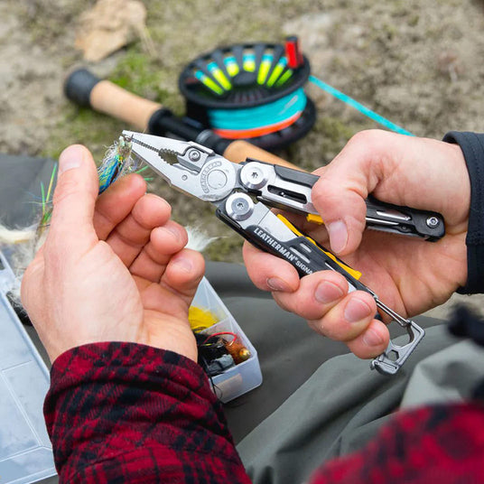 Translation missing: en.Person using a Black & Stainless Leatherman Signal® pliers to adjust a fishing hook