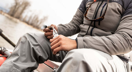 Translation missing: en.Person using a stainless steel Leatherman multitool while fishing, showcasing its utility in outdoor settings