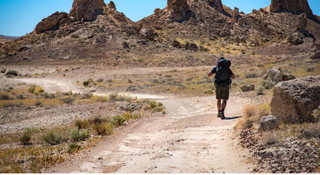 Hiker on a desert trail with hiking gear.