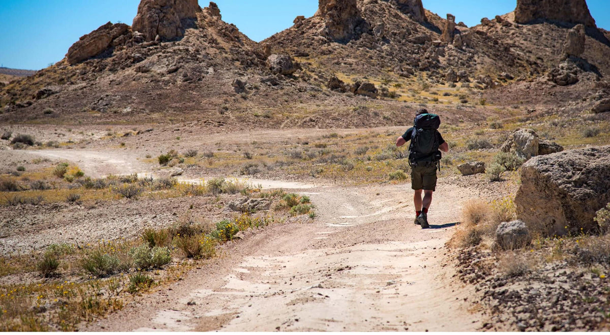 Hiker on a desert trail with hiking gear.