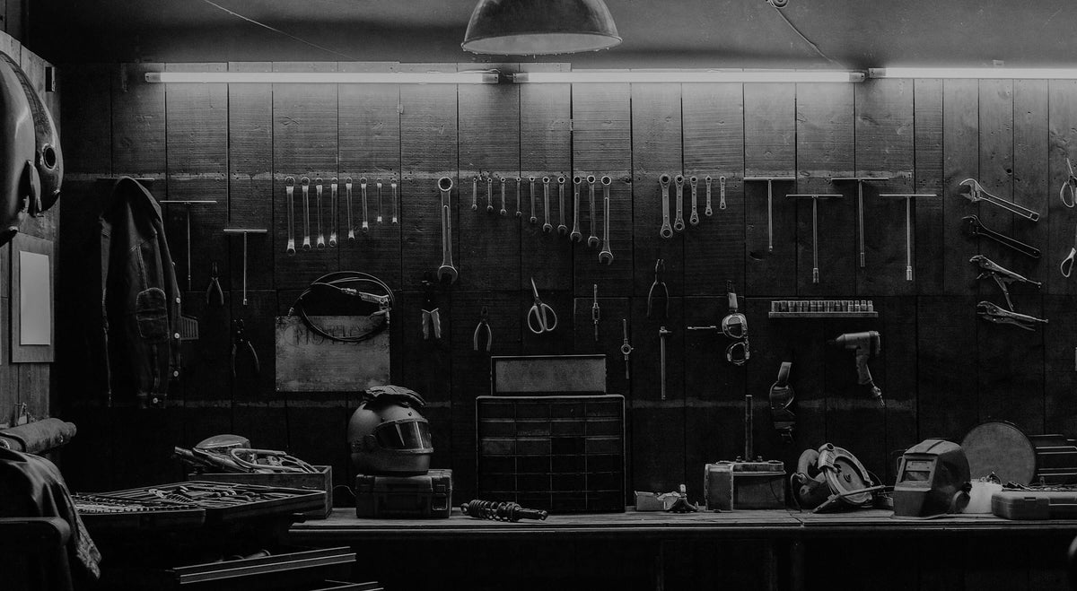 A black and white photo of a workshop wall displaying various tools and equipment.