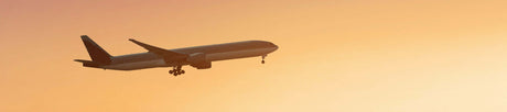 Translation missing: en.Airplane flying against a sunset sky, capturing the essence of travel and adventure