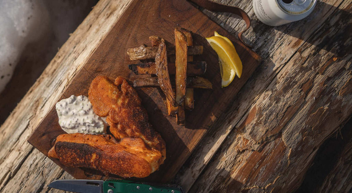 Delicious meal of fish, fries, and sauce on wooden platter.