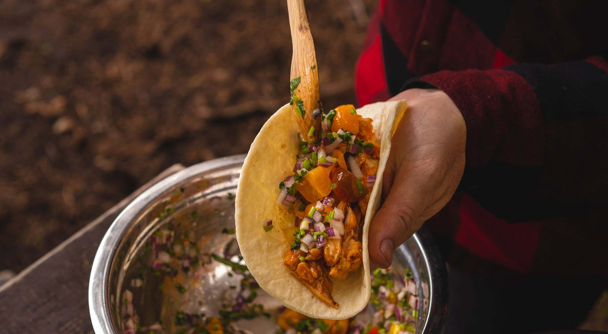Cholula camp taco with delicious filling and fresh toppings being held over a bowl.