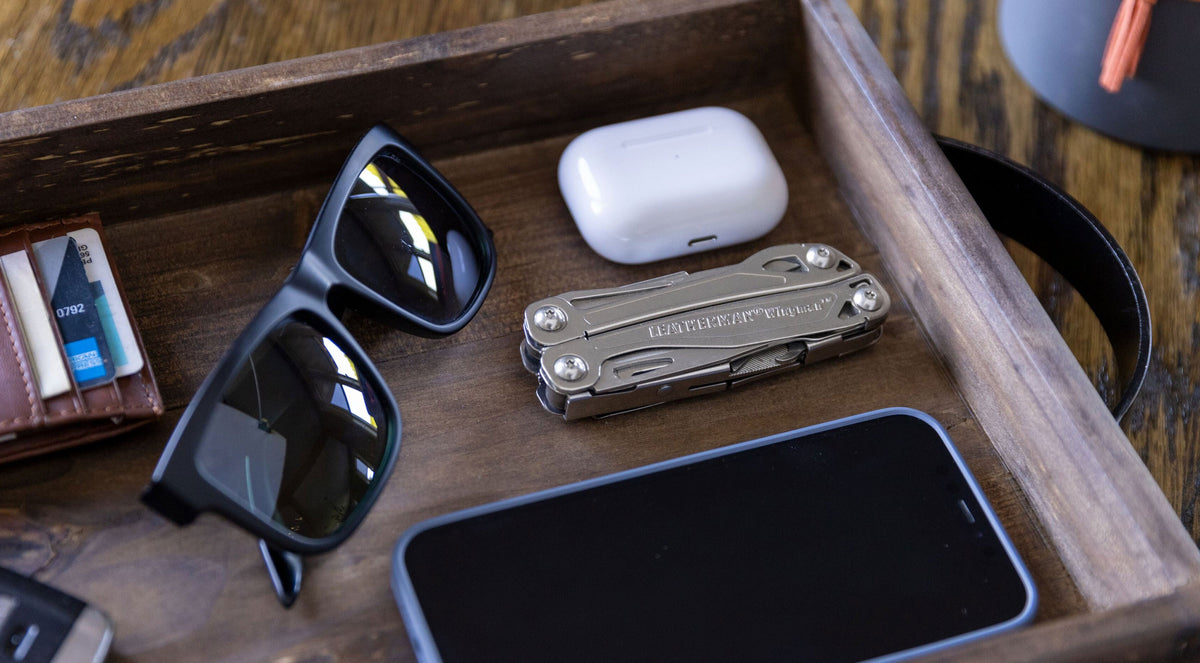 Leatherman Wingman on table with other everyday carry items ike sunglasses and ear pods