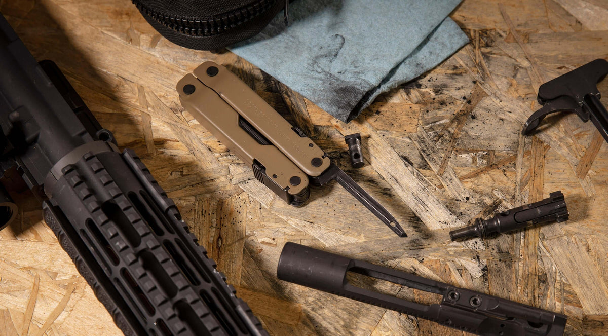 Coyote Tan Super Tool® 300M on a workbench with firearms and cleaning supplies.