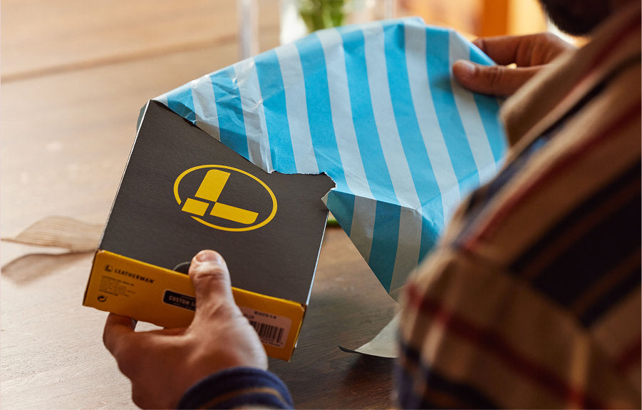Translation missing: en.A man unwraps a present containing a Leatherman box