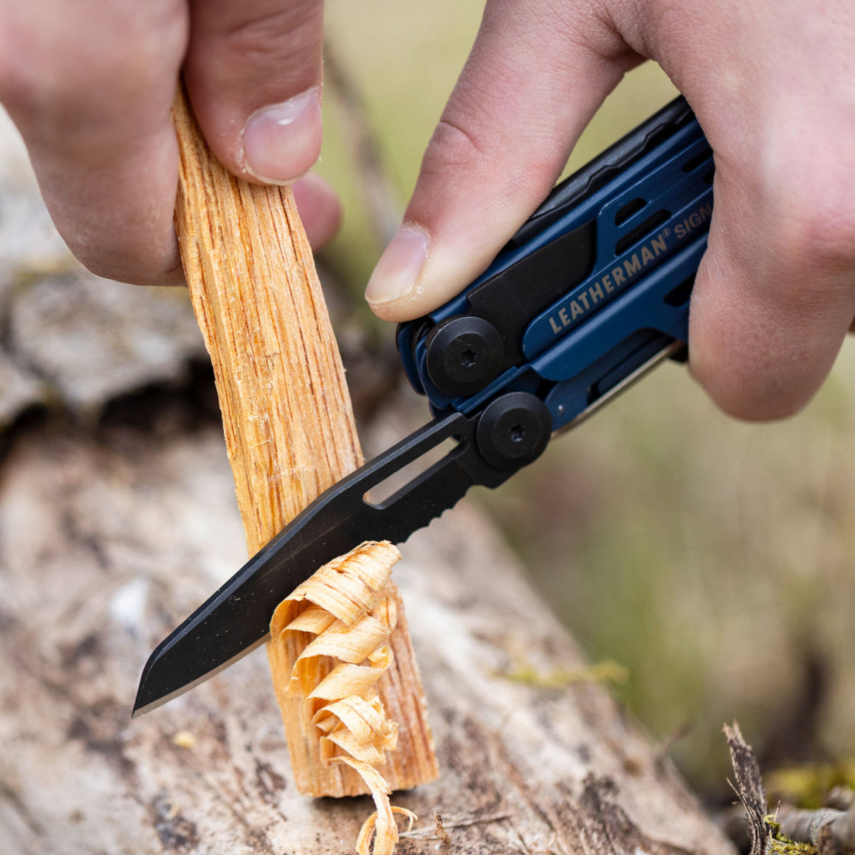 Translation missing: en.A person skillfully uses a Leatherman Signal to cut through a wooden plank, demonstrating precision and care in their work