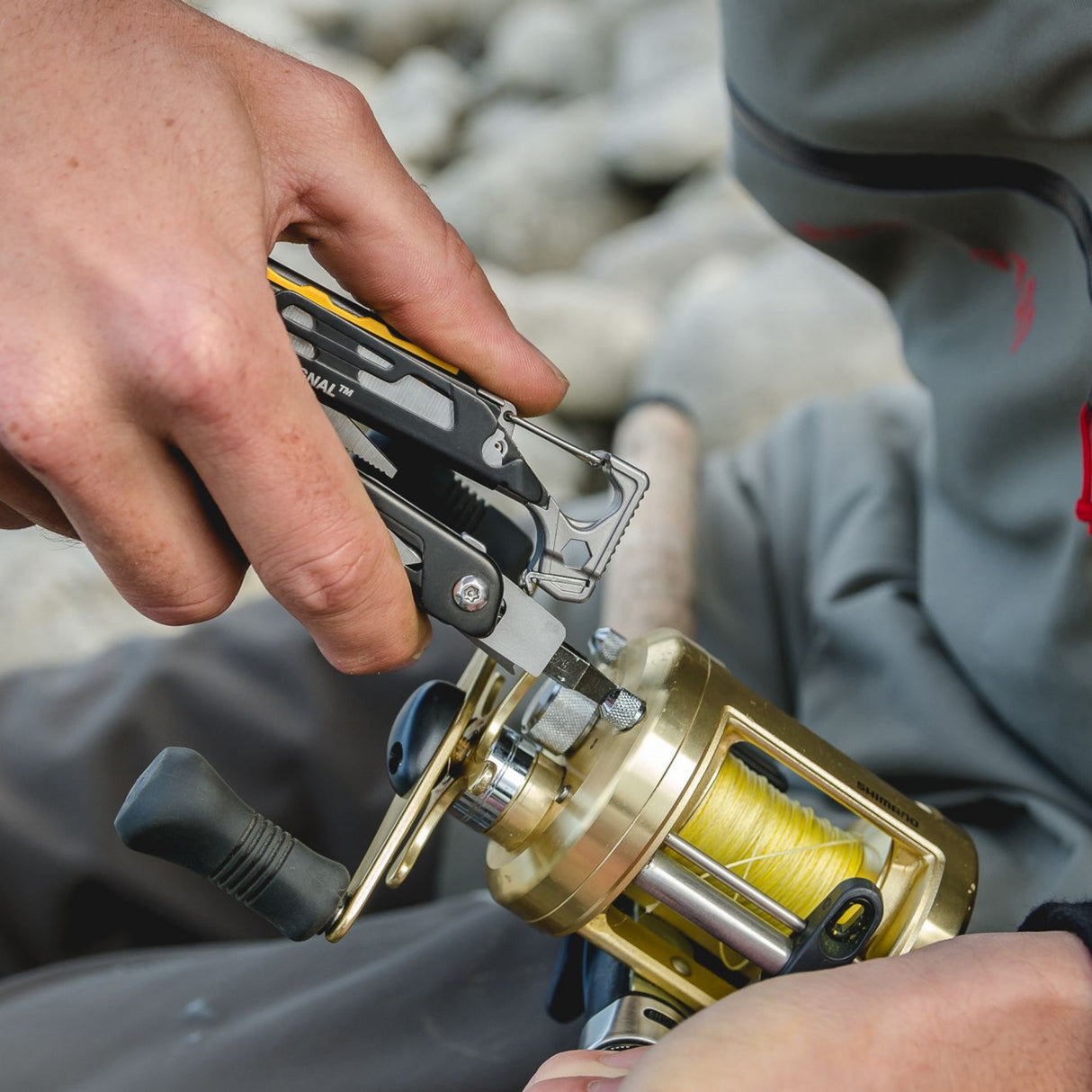 Translation missing: en.A person uses Leatherman Singal to secure a fishing reel, demonstrating a unique fishing technique
