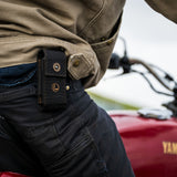 Translation missing: en.A man riding a motorcycle, wearing the Leatherman Black Bronze Nylon Sheath on his side, cruising down a scenic road