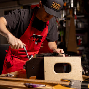 Translation missing: en.Person wearing a red apron repairing electronic equipment at a workbench in a garage workshop