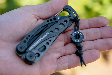 Translation missing: en.Onyx Leatherman Skeletool® CX multi-tool in hand with black lanyard bead showcasing sleek design and functionality