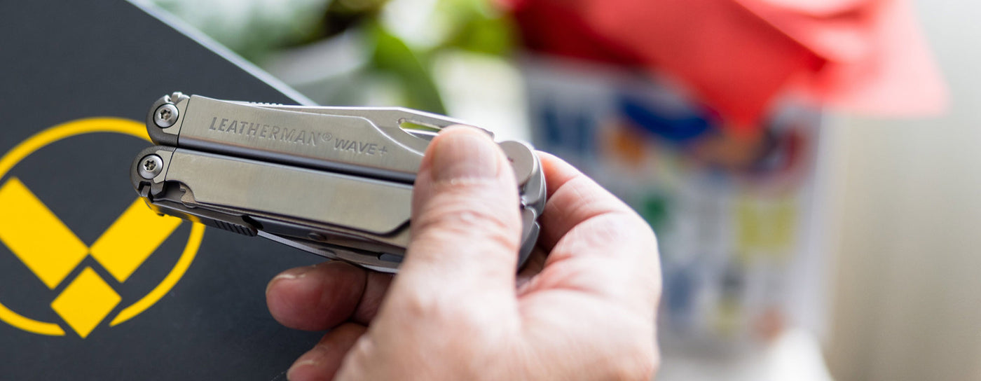 Translation missing: en.A Leatherman Wave+ is held by a person, displaying a distinctive logo on its handle