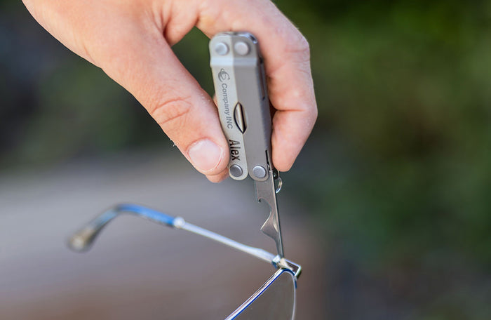 Translation missing: en.A person is grasping a pair of glasses and Leatherman Micra, indicating a potential repair or modification of the eyewear