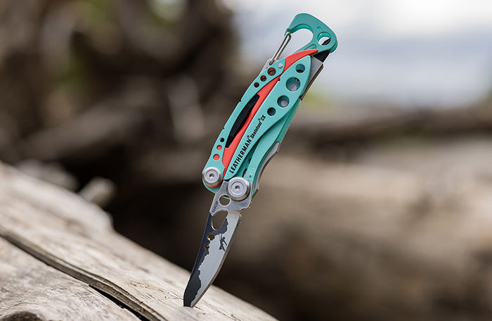 Translation missing: en.Leatherman Skeletool CX inserted in wooden surface, showcasing their metallic finish against the natural wood grain