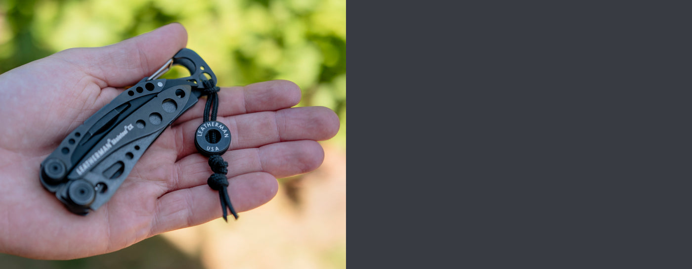 Translation missing: en.Onyx Leatherman Skeletool® CX multi-tool in hand with black lanyard bead showcasing sleek design and functionality