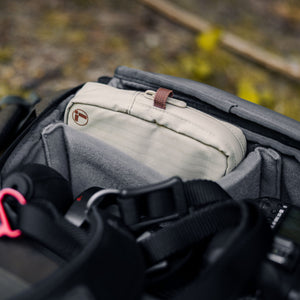 Translation missing: en.A Leatherman Tool Pouch in Mossy Fog color is neatly packed inside a camera gear backpack, surrounded by padded compartments and photography equipment, highlighting the pouch’s portability and organizational fit for on-the-go adventures