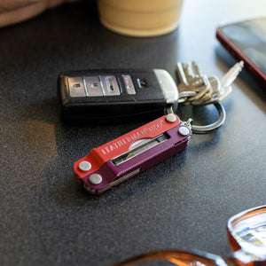 Translation missing: en.A Mulled Wine Leatherman Micra® attached to a keyring with car keys resting on a dark tabletop