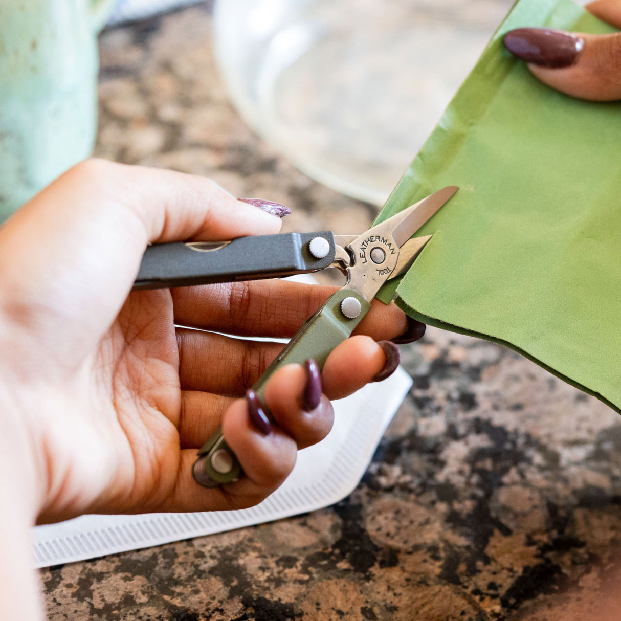 Translation missing: en.A person using the scissors on a Spruce Leatherman Micra® to cut a green pouch