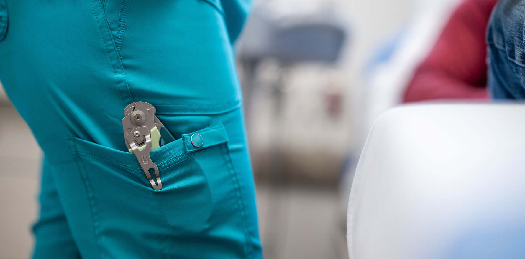 A nurse featuring wearing scrubs and a pair of Leatherman Raptor Rescue shears in their pocket, suggesting readiness for tasks.