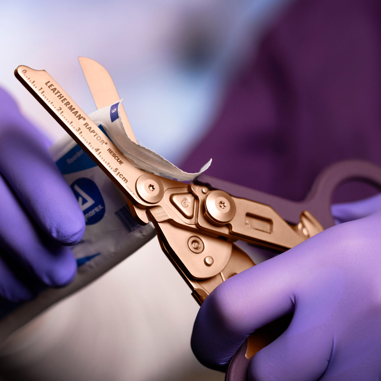 Translation missing: en.Rose Gold Raptor® Rescue shears cutting open medical packaging held by gloved hands