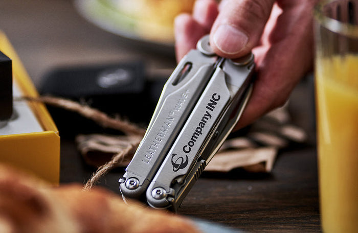 Translation missing: en.Stainless steel Leatherman Wave® Plus customized with 'Company INC' logo, showcased in a lifestyle setting