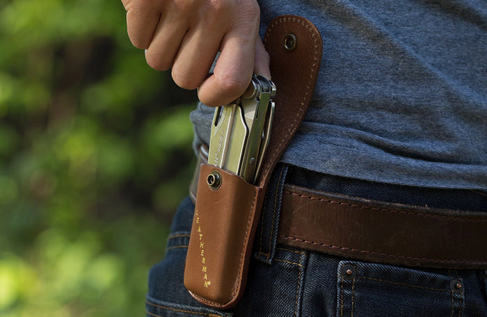 Translation missing: en.A person reaching for a Stainless Steel Leatherman Wave® Plus multi-tool in a brown leather sheath on their hip