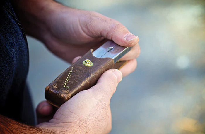 Translation missing: en.Person holding a used brown Leatherman leather sheath with a used Leatherman PST tool inside