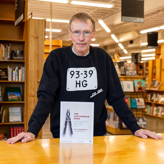 Translation missing: en.Tim Leatherman stands behind a copy of The Leatherman Book at a bookstore